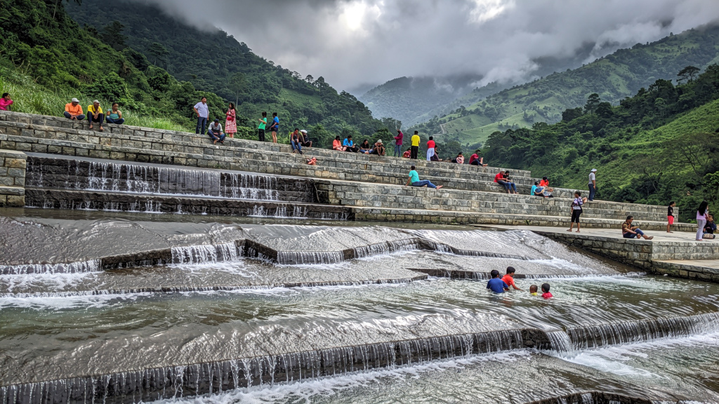 Families enjoying the flowing water on Bhushi Dam's stone steps during monsoon